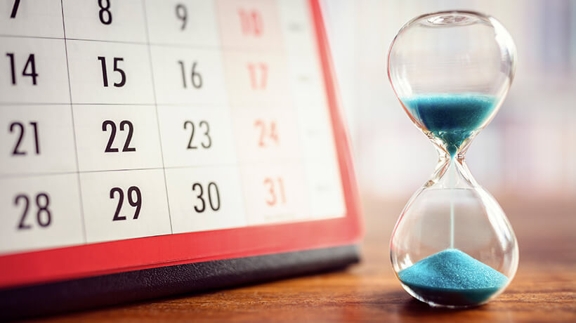 Hourglass sitting near calendar