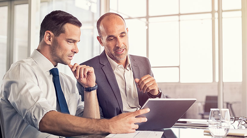 Two men discussing subject matter on a tablet